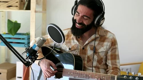Hispanic man performing music and singing into microphone at home sound recording studio. The man pl