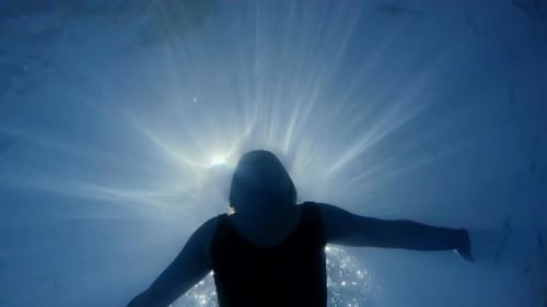Underwater View of Woman Swimming Toward Sunlight