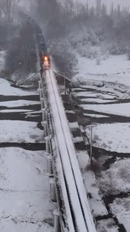 Passenger Train Crossing Snowy Bridge in Winter