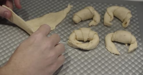 Close up of a Baker Making Dough Into Croissants. Multiple have already been prepared.