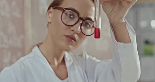 Joven química haciendo pruebas o experimentos en un laboratorio comprobando una mezcla química en un
