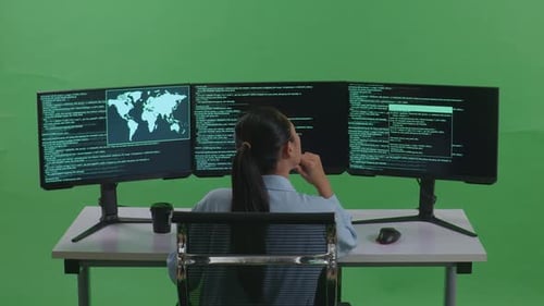Back View Of Asian Woman Thinking While Write Code With Multiple Screens In Green Screen