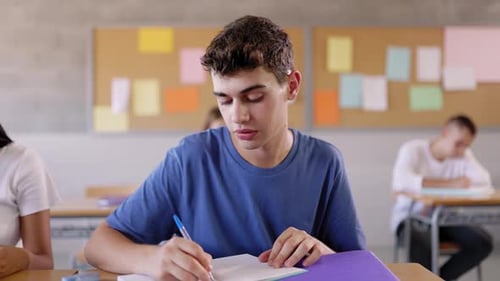 High School Young Student Writing to Notebook in Class Lecture