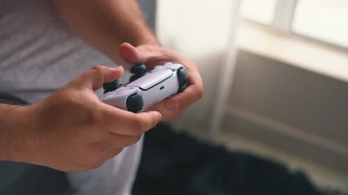 Close up of male hands playing video game by a open window light in slow motion