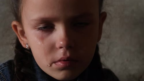 Portrait d'une petite fille avec des larmes sur le visage assise dans un abri anti-bombes