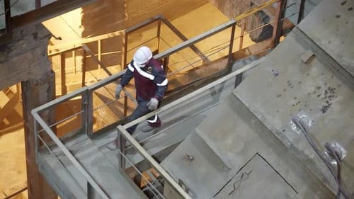 Worker Walking on Platform in Dimly Lit Factory