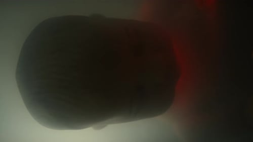 Person Lays with Red Light Moving on Head