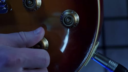 Adjusting tone knobs and volume of electric guitar, close up. Vertical video