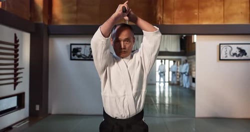 Man Practices with Sword in Martial Arts Dojo