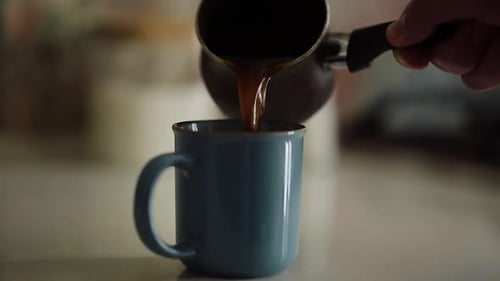 Pouring black coffee from a jezve close up
