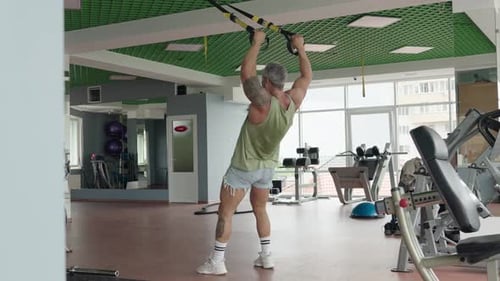 Mann trainiert mit Suspensionstrainer im modernen Fitnessstudio