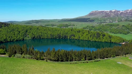 Stunning Aerial View of Clear Blue Lake Ringed by Forest and Mountains