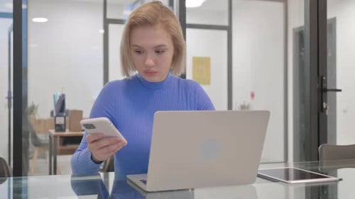 Woman Using Laptop and Smartphone in Office