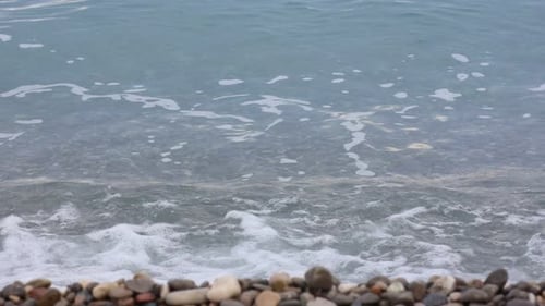 Bela vista do mar ondulado e seixos na praia, de perto