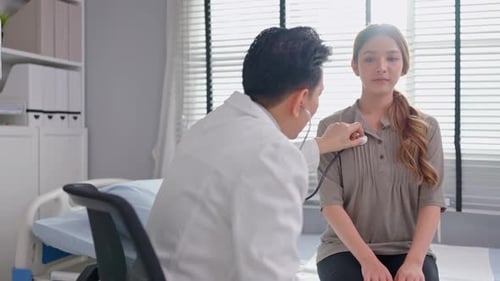 Asian cardiologist doctor listen to heartbeat patient woman in hospital.