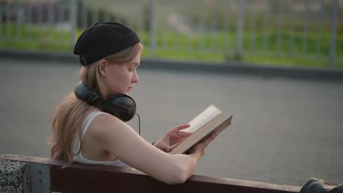 Woman Reads Book on Bench in Urban Setting
