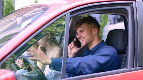 Close Up of Caucasian Handsome Man Sitting in Car with Pretty Girlfriend and Talking on Cellphone