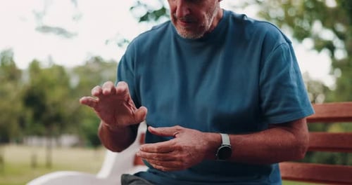 Senior, man and hands with joint inflammation on park bench for discomfort