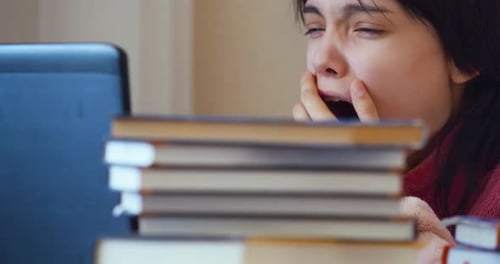 Yawning Caucasian Teenager Girl with in Front of Laptop at Home Online Education