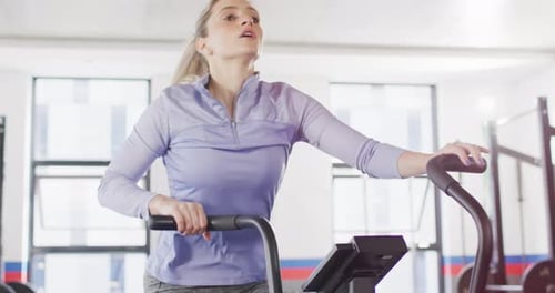 Video of determined caucasian woman on exercise bike working out at a gym