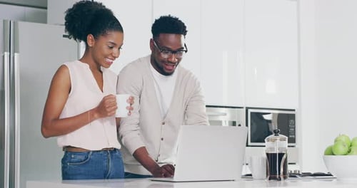 Smiling Couple Using Laptop in Modern Kitchen