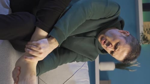 Vertical Video of Mature man with severe foot pain rubbing his ankles. Fatigue symptoms.