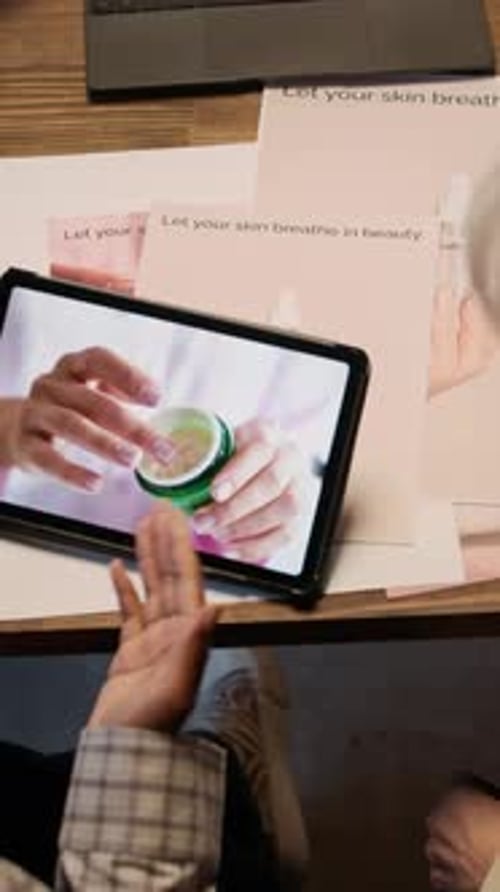 Hands Holding Tablet Displaying Cream Product in Studio