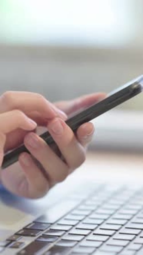 Close up of Woman Using Smartphone Near Laptop, Vertical Video