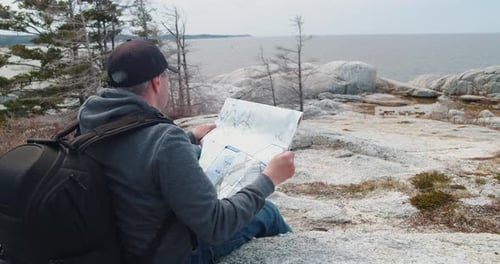 Man Reads Map Near the Ocean