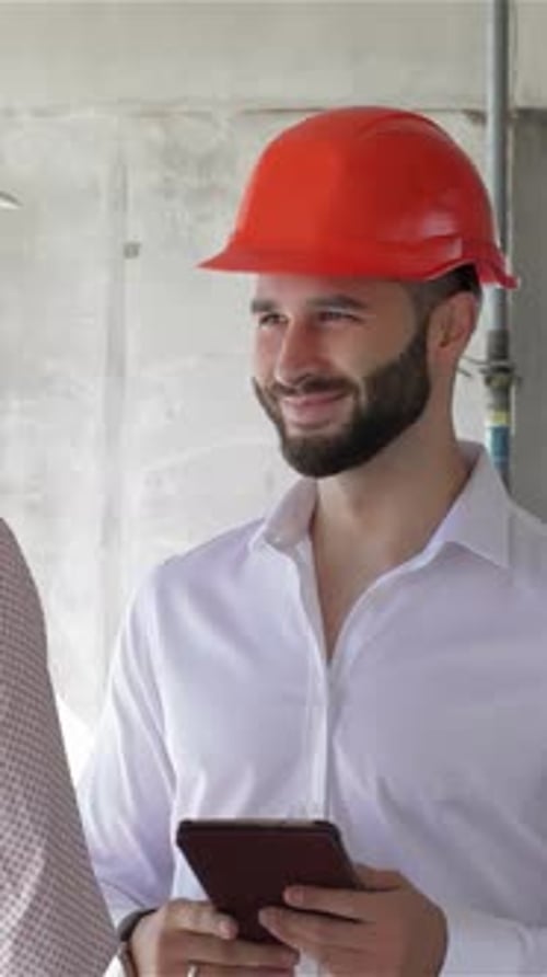 Construction Engineer Discusses Plans While Holding a Digital Tablet