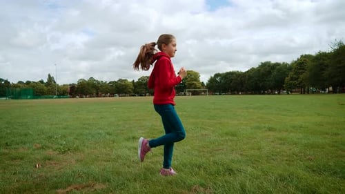Mädchen läuft auf Gras im Park in Großbritannien Kind joggt durch Freizeitgelände in Großbritannien Kind bewegt sich