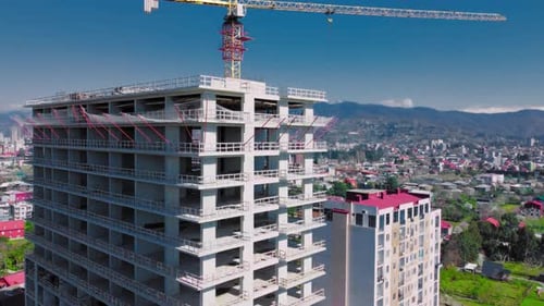 Nuevo complejo de apartamentos altos sin terminar contra el cielo azul, las montañas y el mar