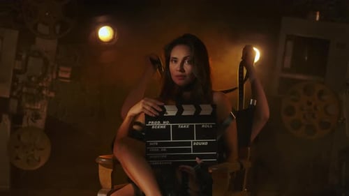 Elegant Woman with Clapperboard in Vintage Film Studio