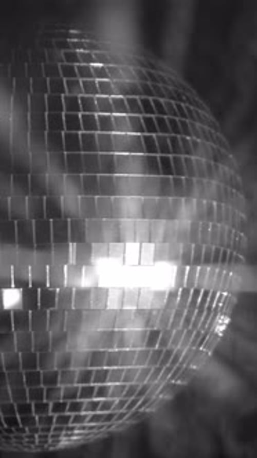Sparkling silver disco ball reflecting bright lights. Vertical