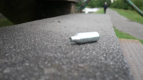 Cilindro perigoso de gás riso de óxido nitroso de cromo caindo em degraus de concreto do parque