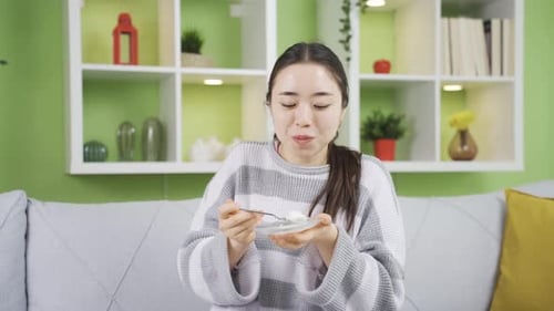 Woman Enjoying a Snack at Home on Couch