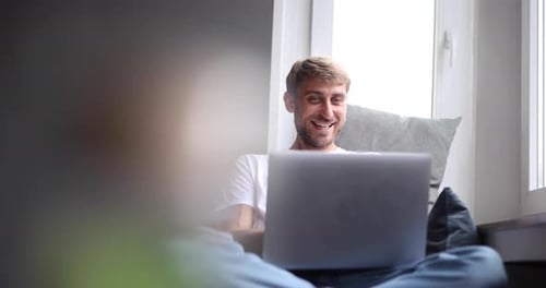 Smiling Man Using Laptop While Relaxing at Home