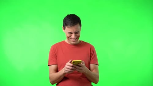 Young Man Smiling at Mobile Phone on Greenscreen