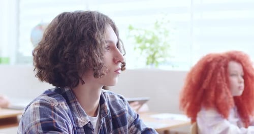Close Up of Face of Caucasian Teen Clever Schoolboy with Long Hair Sitting in Classroom and Rising