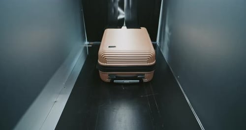 Rose Gold Suitcase Travels Through Dimly Lit Tunnel