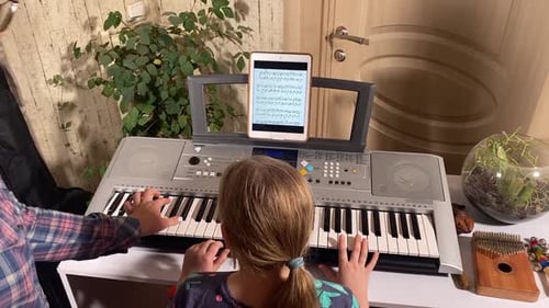 Young Girl Learns Piano with Teacher Indoors