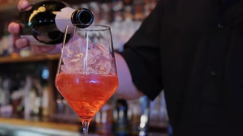 A Bartender is Pouring a Drink Into a Glass Filled with Ice Cubes