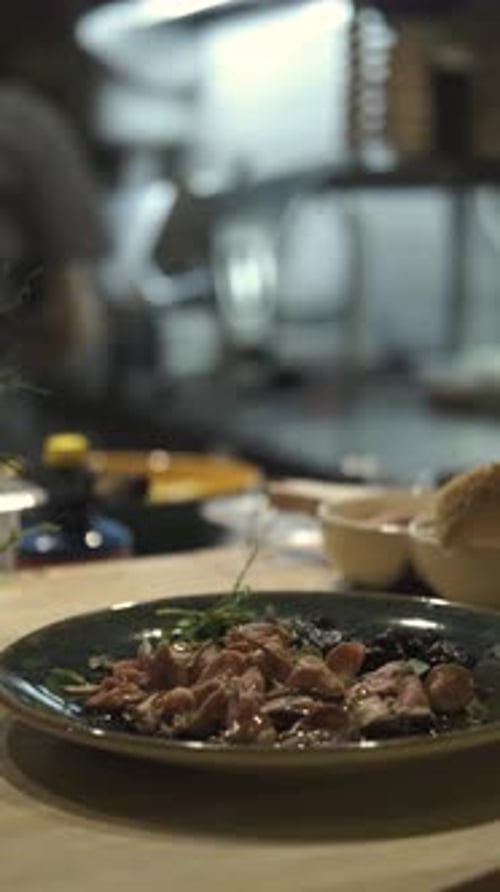 close-up of a dish with meat against the background of a working chef, vertical video