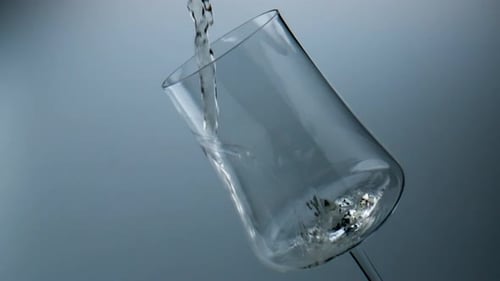 Wine Stream Pouring Glass Closeup. Golden Grape Beverage Filling Beautiful Cup In