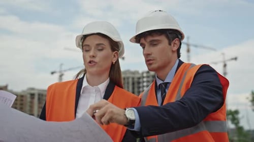 Engineers Review Construction Plans Together at Outdoor Building Site Closeup