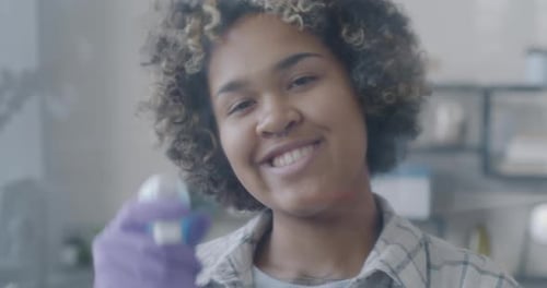 Smiling Woman Cleaning Glass with Gloves Indoors