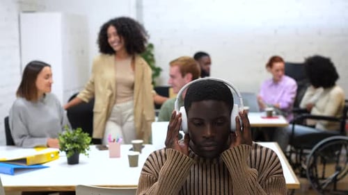 African Man Working Using Laptop and Headphones in a Coworking