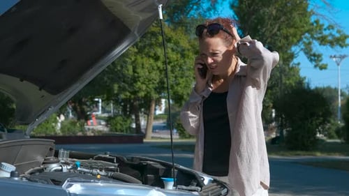 Frustrated Woman Talking on Phone by Broken Down Car