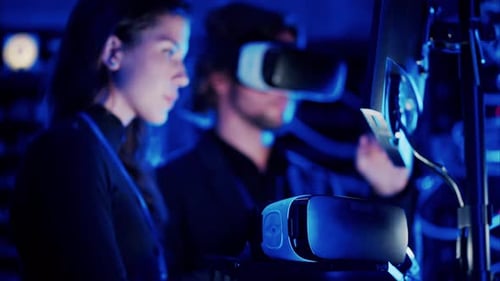 Frau programmiert in einem Serverraum, während ein Mann ein Virtual-Reality-Headset benutzt