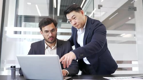 Businessman discussing with colleague at workplace using laptop computer in business office.